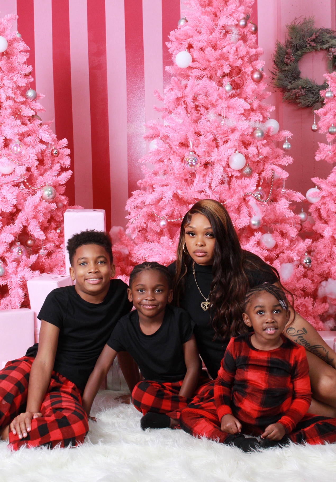 Ms. Khyra with her children in front of a pink holiday backdrop